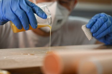 Eldivenli adam sarı sıvı ağacı döker, ahşap işçiliği