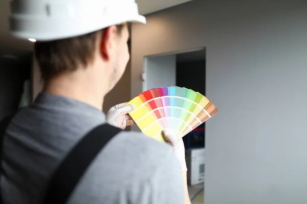 Builder dans le casque détient la palette de couleurs près du mur — Photo