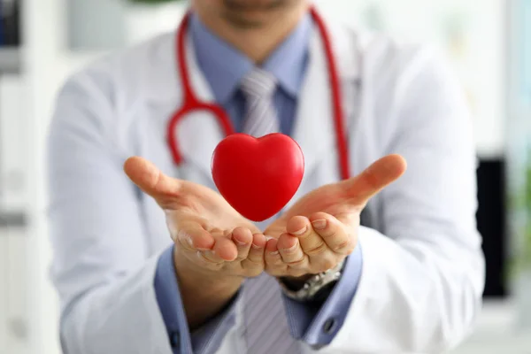 Medicina masculina médico mãos segurando e cobrindo vermelho brinquedo coração — Fotografia de Stock