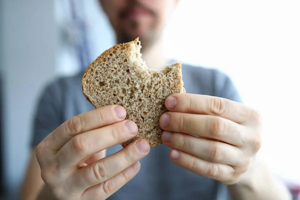 Człowiek pokazuje ugryziony cały zdrowy chleb domowej roboty — Zdjęcie stockowe
