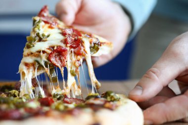 Erkek el, büyük lezzetli taze pizzayı tutuyor.