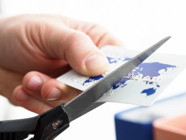 Erkek el makasla bankacılık kartını kesiyor.