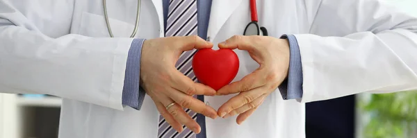 Férfi gyógyszer orvos kezét tartó és borító piros játék szív — Stock Fotó
