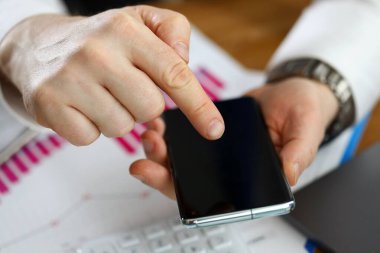 Finansal raporlara dayanan akıllı telefonu elinde tutan adam