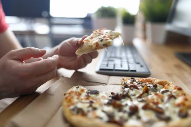 İşyerinde pizza yiyen bir adam var.