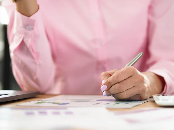 Kvinnan sitter på arbetsplatsen och antecknar på diagrammet — Stockfoto