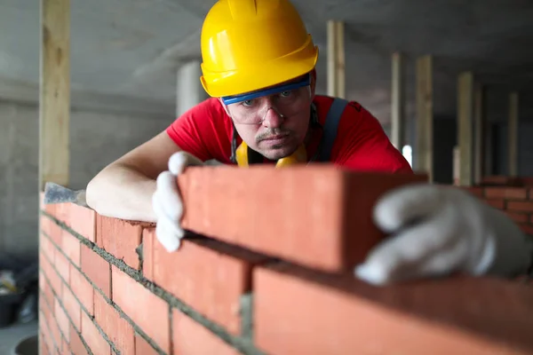Byggaren lägger försiktigt rött tegel på murverket — Stockfoto