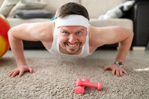 Sorrindo homem fazendo exercícios no tapete no apartamento — Fotografia de Stock