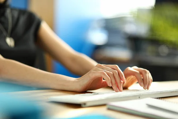 Manos femeninas escribiendo algo en el teclado de la computadora blanca en la mesa de trabajo de la oficina — Foto de Stock