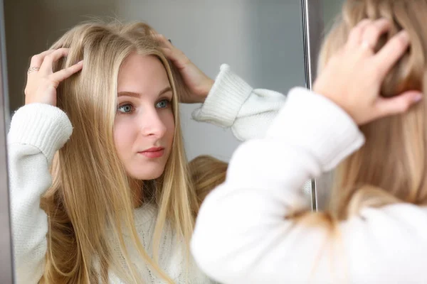 Menina olha espelho na reflexão, endireita o cabelo — Fotografia de Stock