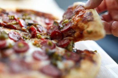 Erkek el, büyük lezzetli taze pizzayı tutuyor.