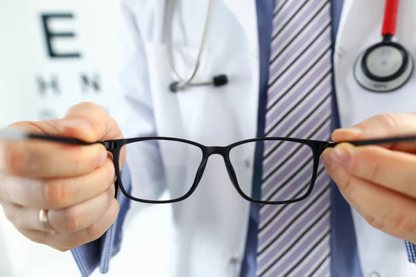 Férfi gyógyszer orvos kezét, amely egy pár fekete szemüveg — Stock Fotó