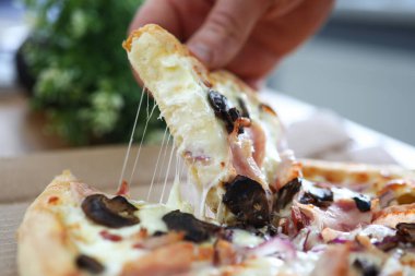 Erkek kolları çalışma masasında büyük bir dilim taze pizza yiyor.