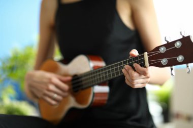 Ukulele çalmayı öğrenen bir kadının yakın çekimi.
