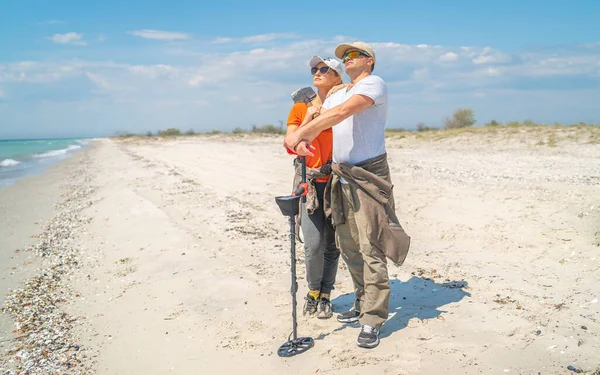 Pareja adulta con detectores de metales en la costa salvaje del mar — Foto de Stock