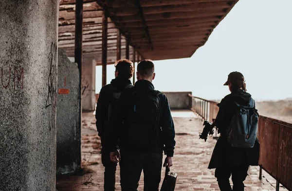 Filming crew watches for a sunset on top of destroyed building