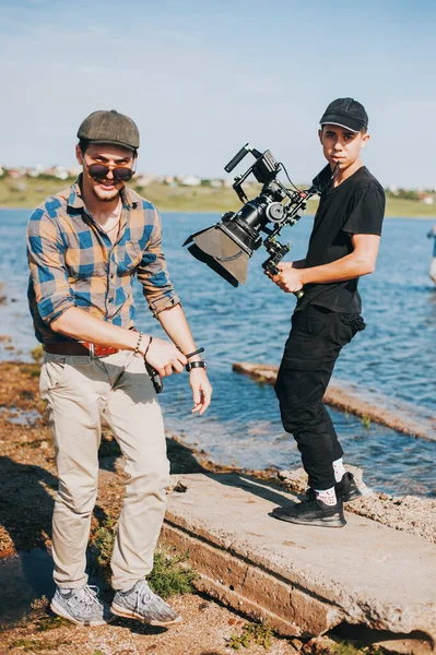 Operator wig rig camera and director smiled while shoot on river coast — Stock Photo, Image