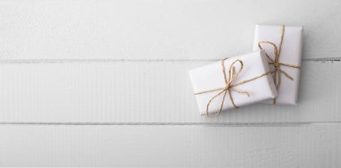 Beyaz ahşap masa üzerindeki iki beyaz hediye paketi