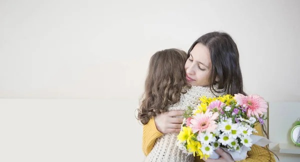 Mère et fille s'embrassent. fleur dans la main de la mère — Photo