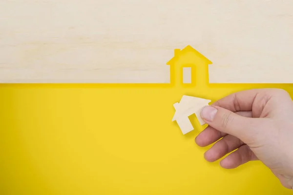 Hand platziert ein Modellhaus auf gelbem Hintergrund. — Stockfoto