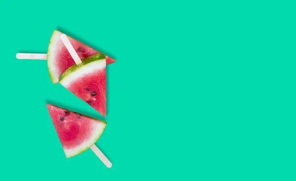 Three slices of watermelon on green background with sticks — Stock Photo, Image