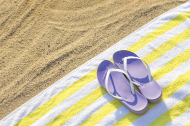 plaj arka planda sarı havlu üzerinde mor terlik