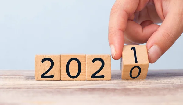 Hand Changing Date From 2020 To 2021 On Wooden Cube Calendar / New Year\'s Concept