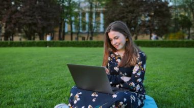 Park açık dizüstü bilgisayar kullanan genç çekici yakışıklı kadın.