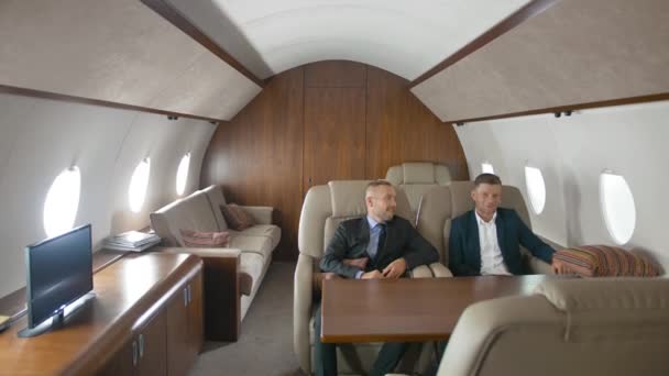 Två affärsmän pratar inne i privat jet. — Stockvideo