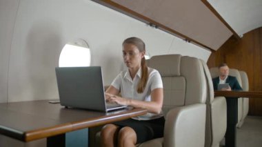 Uçakta dizüstü bilgisayar kullanan iş kadını