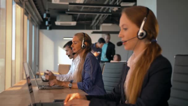 Jovem operadora amigável agente com fones de ouvido trabalhando em um call center . — Vídeo de Stock