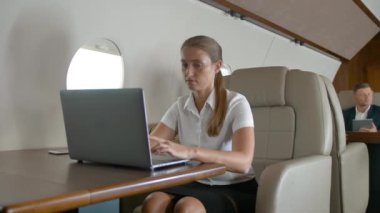 Uçakta dizüstü bilgisayar kullanan iş kadını