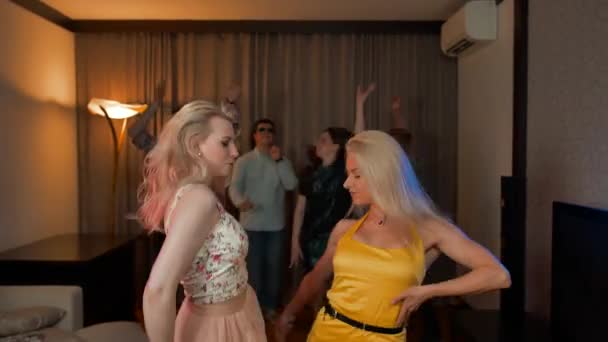 Två attraktiva sexiga flickor dansar på fest med sina vänner bakom. — Stockvideo