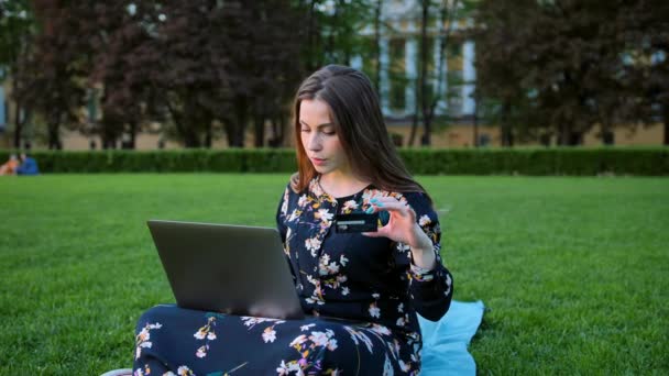 Une fille avec un ordinateur portable et une carte de crédit en plein air — Video