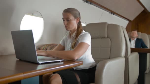 Jeune femme d'affaires utilisant un téléphone portable et un ordinateur portable sur la cabine privée d'un avion . — Video