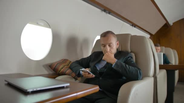 Entrepreneur confiant voyageant sur son jet privé et bavardant sur son téléphone portable . — Video