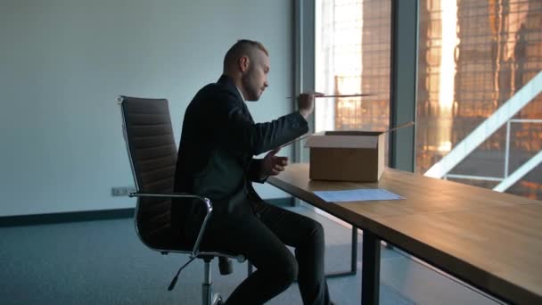 Предприниматель с коробкой для переезда в офис распаковывает вещи — стоковое видео