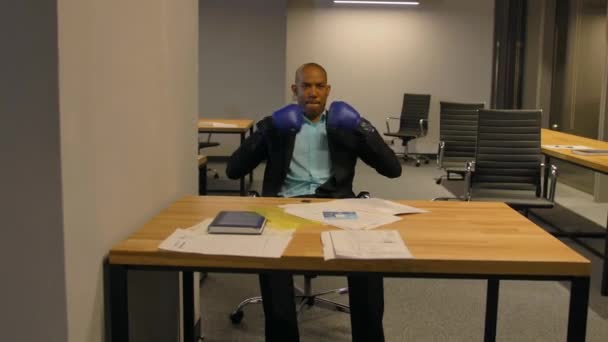 Афроамериканець бізнесмен сидить з боксерські рукавички в офісі — стокове відео