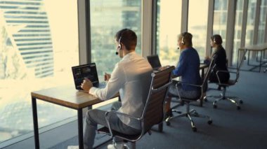 Güzel iş kadın ofiste çalışan kulaklıklar ve yakışıklı genç işadamı arkadan görünüm