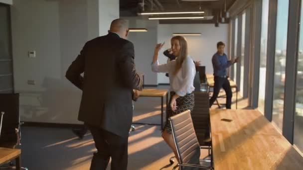 Zakenmensen dansen vrolijk in kantoor voor de camera — Stockvideo