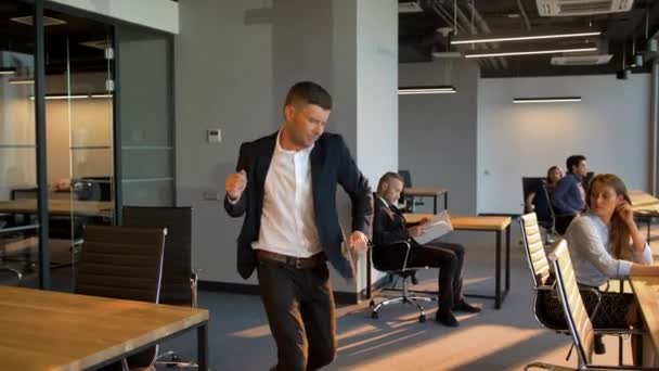 Група бізнесменів, які дивляться на танцювального колегу, вважають, що його поведінка дивна . — стокове відео