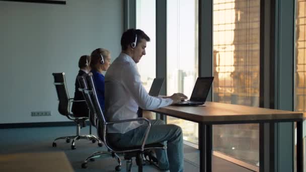 Rij van call centrum agenten te typen achter hun bureau in het kantoor — Stockvideo