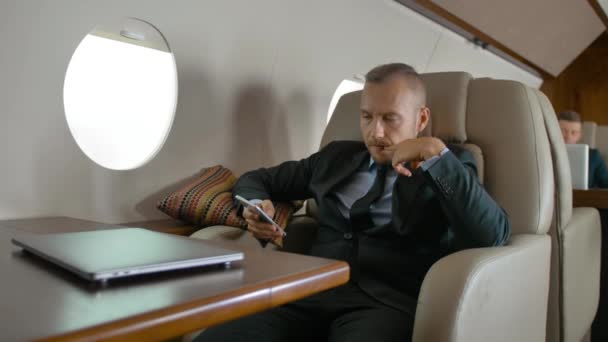 商人在他的私人飞机旅行和聊天在手机上的正式西装 他喜欢豪华级的飞机飞行 慢动作镜头 — 图库视频影像