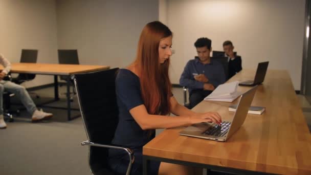 Zeitlupenaufnahme einer hübschen Frau, die einen Laptop benutzt und in die Kamera schaut — Stockvideo