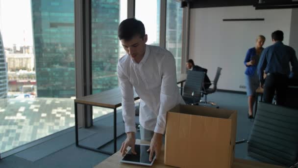 Empreendedor caixa de desembalagem com documentos e equipamentos. Seus colegas caminhando perto no escritório moderno — Vídeo de Stock