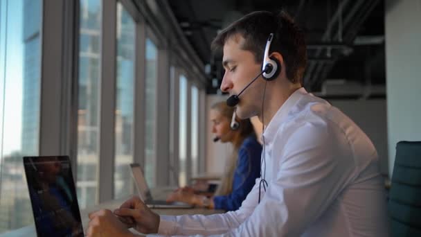 Tampan laki-laki di headset panggilan di kantor bisnis call center — Stok Video