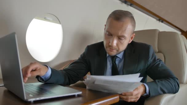 Pohledný muž s MacBookem surfování na Internetu uvnitř luxusní interiér soukromé letadlo — Stock video
