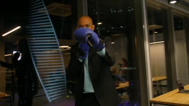 Koncepcja walki biznesowej. Afrykański bokser w rękawiczkach i formalnym garniturze machający rękawicami bokserskimi. — Wideo stockowe