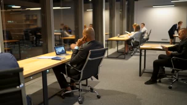 Des hommes d'affaires discutant et utilisant des ordinateurs portables, des tablettes et des dessins au bureau tard dans la nuit 