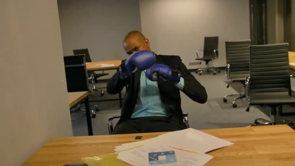 Sportowy lider fighty w koncepcji biznesowej. Afro-amerykański biznesmen siedzi z rękawice bokserskie w biurze — Wideo stockowe